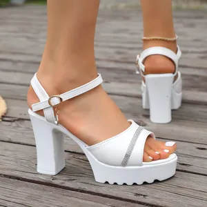 Close-up detail of white platform sandals with sparkling rhinestone strap and chunky heel