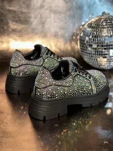 Close-up of sparkling black sneakers with iridescent rhinestones and thick platforms