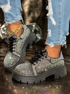 Detail of platform sneakers covered in sparkling multi-color rhinestones and satin laces.