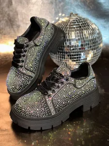 Close-up view of black platform sneakers adorned with sparkling iridescent rhinestones
