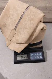 Close-up showing the weight of beige suede embroidered boots on a digital scale