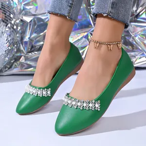 Vista dettagliata di ballerine verdi a punta con fascia decorativa in strass e perle.