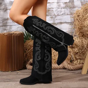 Close-up of black suede Western knee-high boots with white embroidery and side zipper