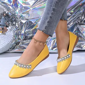 Primo piano di eleganti scarpe basse gialle a punta con dettagli in strass e perle