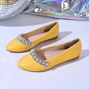 Dettaglio di ballerine gialle a punta con decorazioni in strass e perle preziose