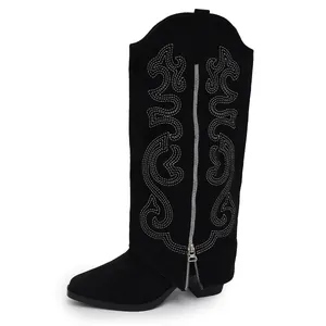 Detail view of black suede western knee-high boots with white embroidery and side zipper.