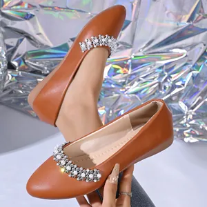 Primo piano di scarpe basse marroni stile francese con eleganti perle e strass luccicanti.