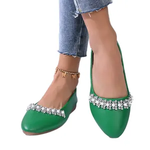 Eleganti scarpe basse a punta verdi con decorazione di strass e perle su fondo bianco