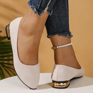 Detailed view of beige suede pointed-toe flats with gold-accented square heels