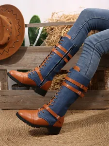 Detailed view of denim and leather patchwork knee-high boots with buckle straps and block heel.