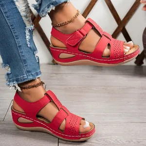 Close-up detail of red platform wedge sandals with cross straps and decorative stitching
