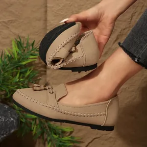 Close-up of flexible beige women's loafers with elegant tassel and whipstitch detail