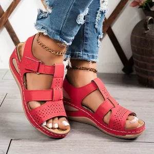 Detailed close-up of stylish red wedge sandals featuring laser-cut patterns and velcro straps