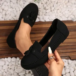 Detailed close-up of black suede loafers featuring decorative tassels and stitching