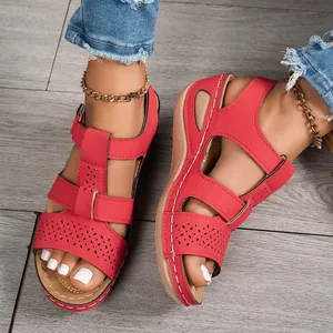 Detailed macro view of red platform wedge sandals with intricate floral hollow-out patterns