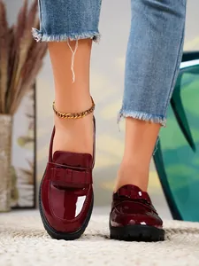 Close-up of burgundy patent leather loafers with stylish bow detail and thick black soles