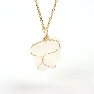 Close-up view of an irregular clear quartz pendant with handmade gold wire wrapping.