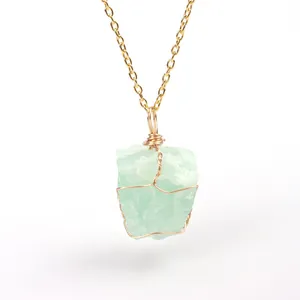Detail macro view of a natural irregular green raw stone pendant with gold wire wrapping