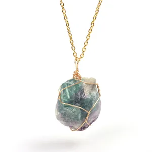 Close-up detail of a natural raw fluorite crystal pendant with handmade gold wire wrapping.