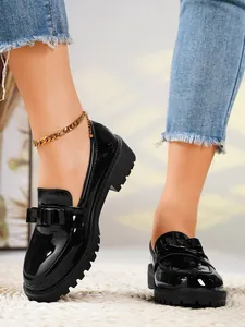 Detail view of stylish black patent leather loafers with bow and platform sole