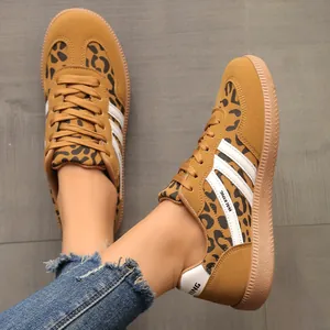Close-up view of leopard print German trainer sneakers with iconic white stripes on floor.