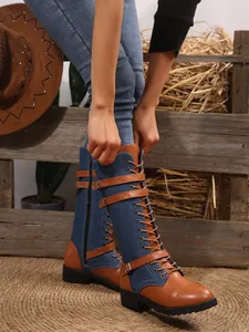Detail of tall denim leather boots with buckle straps and laces in rustic setting