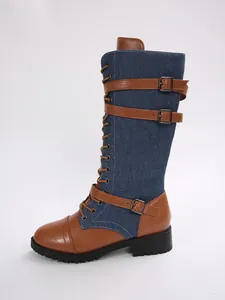 Detailed side view of denim and brown leather patchwork knee-high boots with buckles.