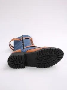 Close-up of denim and leather spliced knight boots showing sole and buckle detail