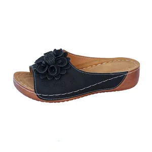 Close-up of women's wedge sandals featuring navy blue floral decoration and white stitching