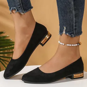 Close-up view of elegant black suede pointed-toe flats featuring a gold block heel detail
