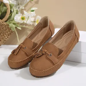 Detailed view of women's brown suede loafers featuring elegant tassel and hand-stitched seams