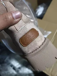 Primo piano della toppa con logo in pelle marrone sul tallone di uno stivale da neve beige
