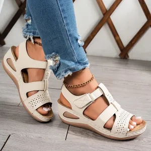 Detail view of cream platform wedge sandals with hollow out patterns and stitching.