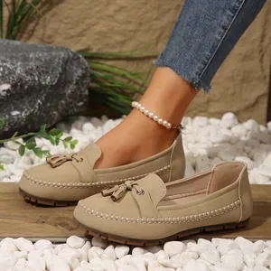 Close-up of stylish beige women's tassel loafers featuring decorative hand-stitching