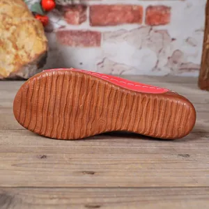 Close-up of the non-slip rippled brown sole on red women's casual wedge slide sandals
