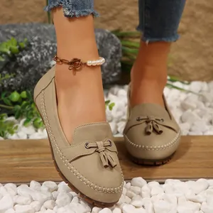 Close-up of khaki suede loafers featuring elegant tassel and white stitching details
