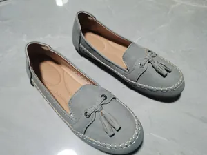 Detailansicht von grauen Quasten-Loafers mit weißen Nähten