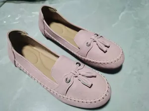 Detailansicht der rosa Damen-Slipper mit Quasten, weicher Sohle und weißen Ziernähten