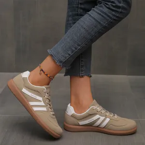 Close-up detail of women's khaki retro German Army Trainers with white stripes on feet.