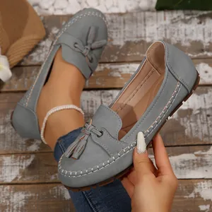 Detail shot of the grey faux-leather texture and tassel ornament on these chic women's loafers