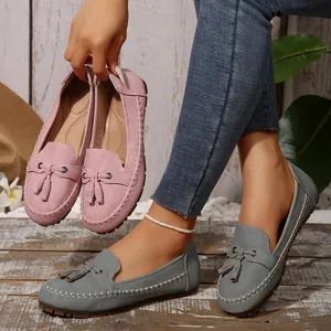 Detail view of stylish women's tassel loafers in pink and grey soft suede finish.
