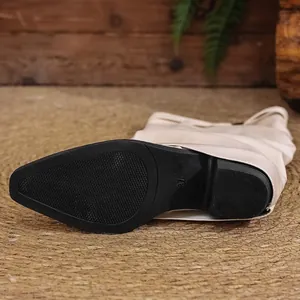 Detailed macro view of the non-slip black rubber sole on stylish cream-colored knight boots