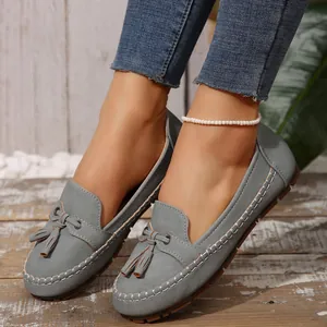 Stylish grey loafers for women with tassel detail on a rustic wooden background