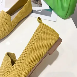 Close-up of yellow flyknit flat shoes showing breathable knitted texture.
