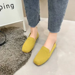 Detailed close-up of yellow knitted square-toe flats worn on feet in a cozy setting