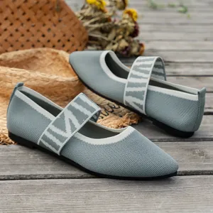 Detailed view of grey fly-knit pointed Mary Jane shoes on a rustic wooden surface.