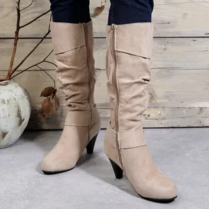 Close-up detail of beige suede mid-calf boots featuring a slouched shaft and side zipper
