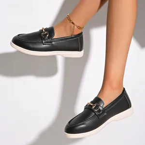 Nahaufnahme von schwarzen Damen-Loafers mit goldener Metallschnalle am Modellfuß