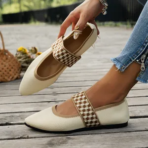 Close-up of beige pointed-toe flyknit flat shoes with checkered strap on wooden deck
