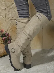 Detalle de las botas de gamuza beige con hebilla plateada y efecto de caña caída
